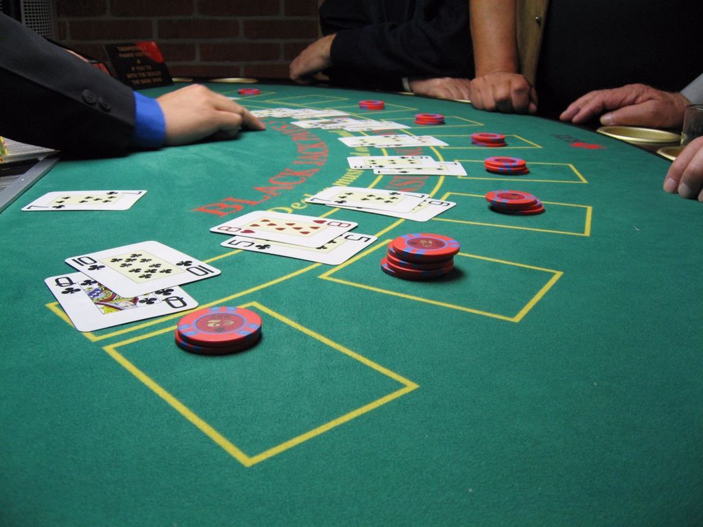 **Partie de blackjack en casino – cartes et jetons disposés sur table de jeu verte**
