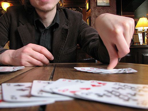 **Partie de rami – joueur posant des cartes sur une table en bois, jeu de cartes traditionnel**
